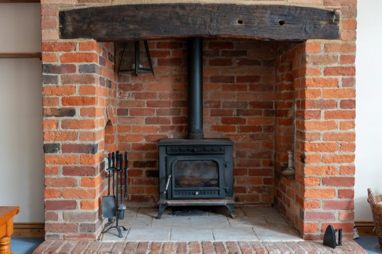 Modern cast-iron wood stove with a red brick surround in