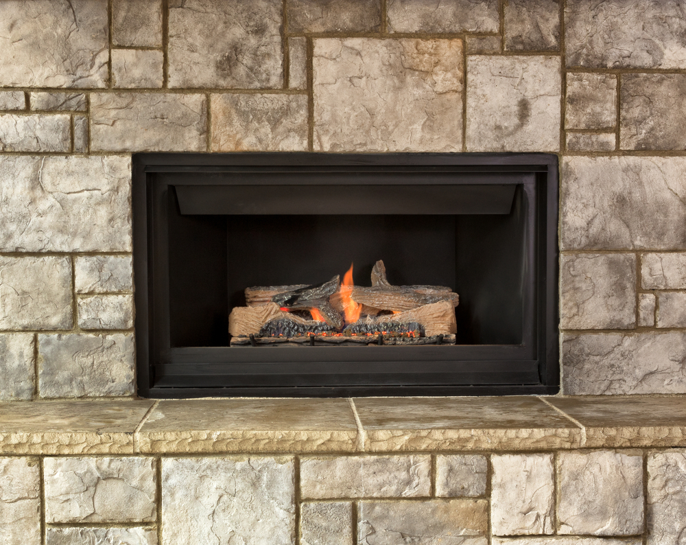 Burning natural gas fireplace surrounded by stone